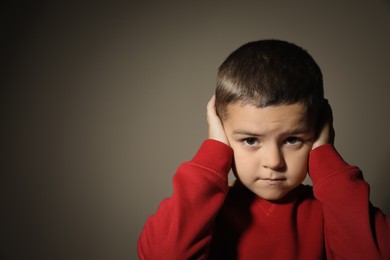Scared little boy on beige background, space for text. Domestic violence concept