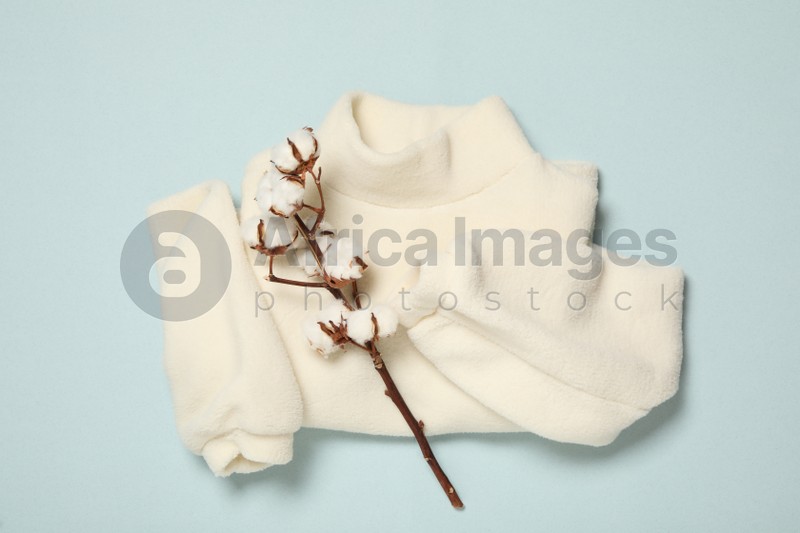 Photo of Warm sweater and cotton flowers on light blue background, flat lay. Autumn season