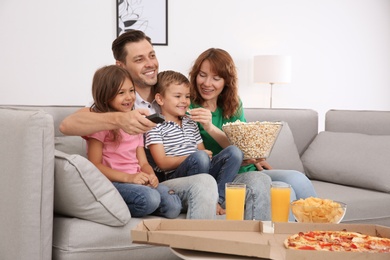 Family watching TV with popcorn in room