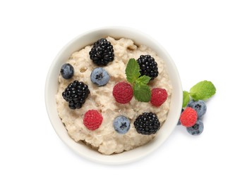 Tasty oatmeal porridge with blackberries, raspberries and blueberries in bowl on white background, top view
