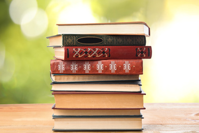 Collection of different books on wooden table against blurred green background