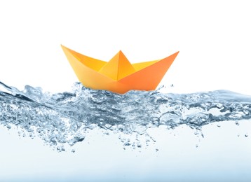 Handmade orange paper boat floating on clear water against white background 
