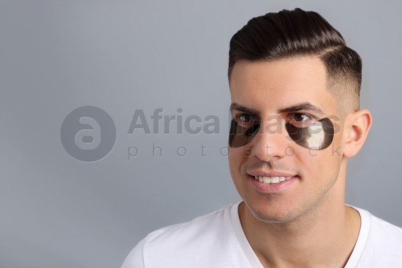 Man with dark under eye patches on grey background. Space for text