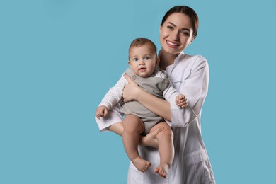 Photo of Young pediatrician with cute little baby on light blue background. Space for text
