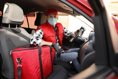 Courier in protective mask and gloves with thermobag inside car. Food delivery service during coronavirus quarantine