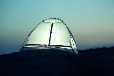 Small camping tent glowing in twilight outdoors