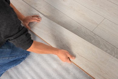 Photo of Professional worker installing new laminate flooring, closeup. Space for text