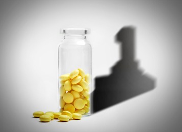 Doping concept. Yellow pills in glass bottle with first place shadow on light background