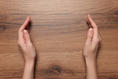 Woman holding on wooden table, closeup of hands. Space for text