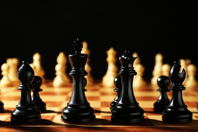 Photo of Chess pieces on wooden board against dark background. Competition concept