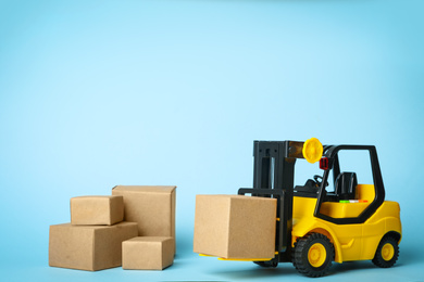 Toy forklift with boxes on blue background. Logistics and wholesale concept