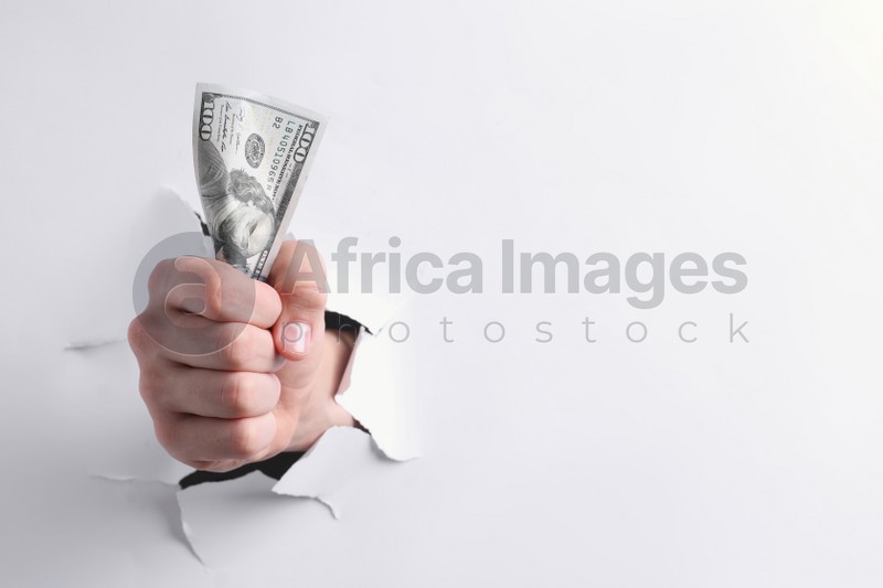 Photo of Man breaking through white paper with money in fist, closeup. Space for text