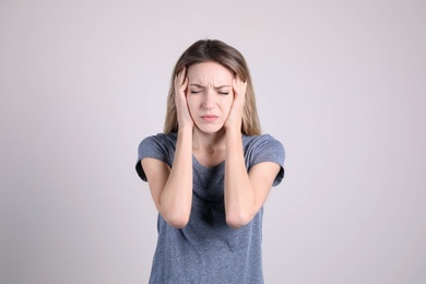 Portrait of stressed young woman on light background
