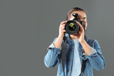 Young woman with camera and space for text on gray background. Professional photo studio