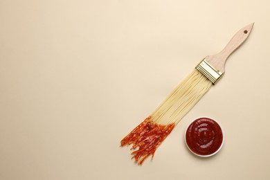 Photo of Brush painting with spaghetti dipped in ketchup on beige background, flat lay. Space for text. Creative concept