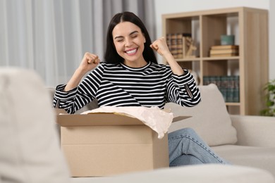 Photo of Emotional young woman with parcel at home. Internet shopping