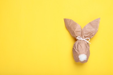 Photo of Easter bunny made of craft paper and egg on yellow background, top view. Space for text