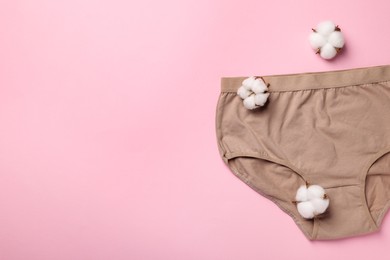 Photo of Beige women's underwear and cotton flowers on pink background, flat lay. Space for text