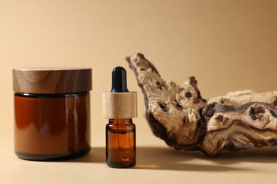 Photo of Jar with luxury cream, bottle of essential oil and tree bark on dark beige background