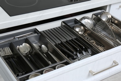 Open drawer with stainless steel utensil set, closeup. Order in kitchen
