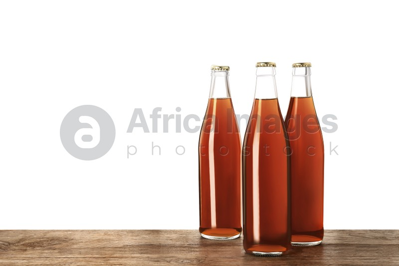 Photo of Bottles of delicious kvass on wooden table against white background