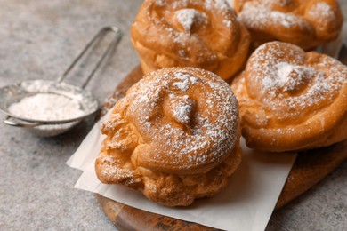 Photo of Delicious profiteroles with powdered sugar on grey table, closeup. Space for text