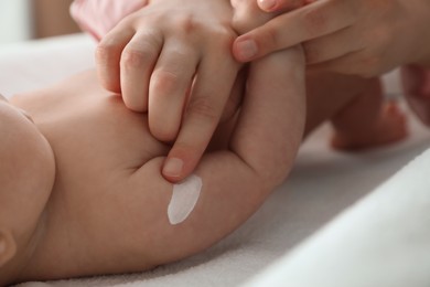 Photo of Mother applying body cream on her little baby, closeup