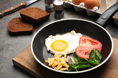 Pan with fried sunny side up egg, cheese and tomato on table