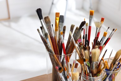 Holders with many different paintbrushes indoors, closeup