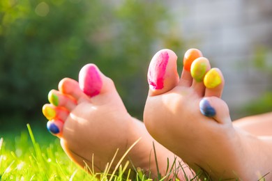 Teenage girl with painted toes on green grass outdoors, closeup