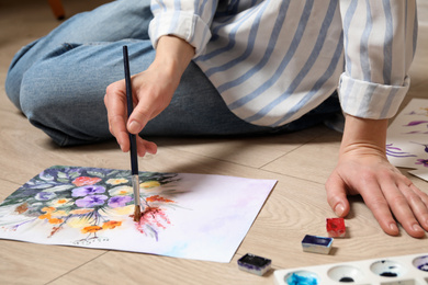 Woman painting flowers with watercolor on floor, closeup