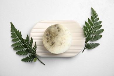 Soap bar with dish and green leaves on white background, top view. Eco friendly personal care product