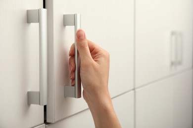 Photo of Woman opening cabinet door at home, closeup