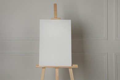 Wooden easel with blank canvas on light background