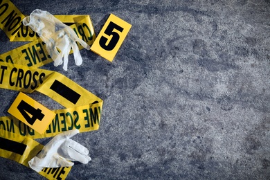 Photo of Crime scene markers, tape and gloves on grey stone table, flat lay