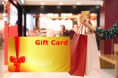 Image of Store gift card. Woman with shopping bags in mall, closeup