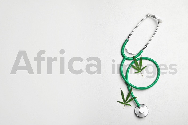 Stethoscope and hemp leaves on white background, flat lay. Space for text