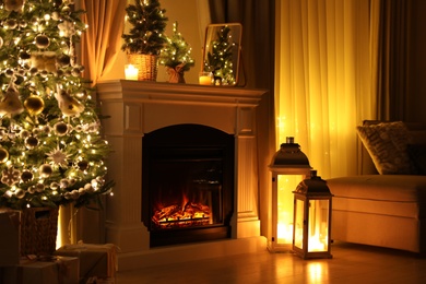 Beautiful fireplace, Christmas tree and other decorations in living room at night. Interior design
