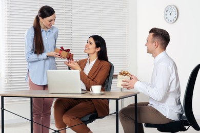 Colleagues presenting gifts to woman in office
