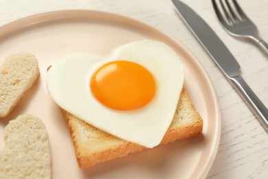 Photo of Plate with heart shaped fried egg served on white wooden table, closeup