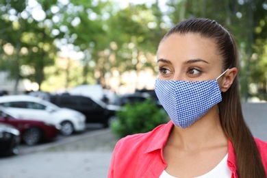 Woman wearing handmade cloth mask outdoors, space for text. Personal protective equipment during COVID-19 pandemic