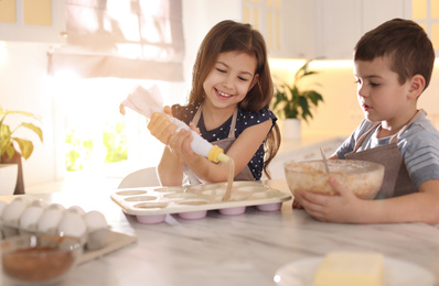 Cute little children cooking pastry in kitchen at home