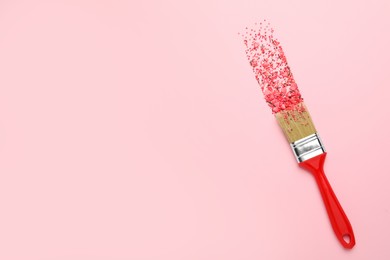 Photo of Brush painting with red sprinkles on pink background, top view. Space for text. Creative concept