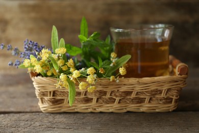 Photo of Tasty herbal tea, fresh lavender flowers and linden branches on wooden table, closeup