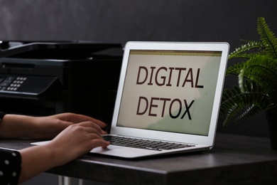 Photo of Woman working with laptop at table in office, closeup. Digital detox concept