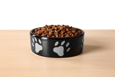 Dry dog food in pet bowl on wooden surface