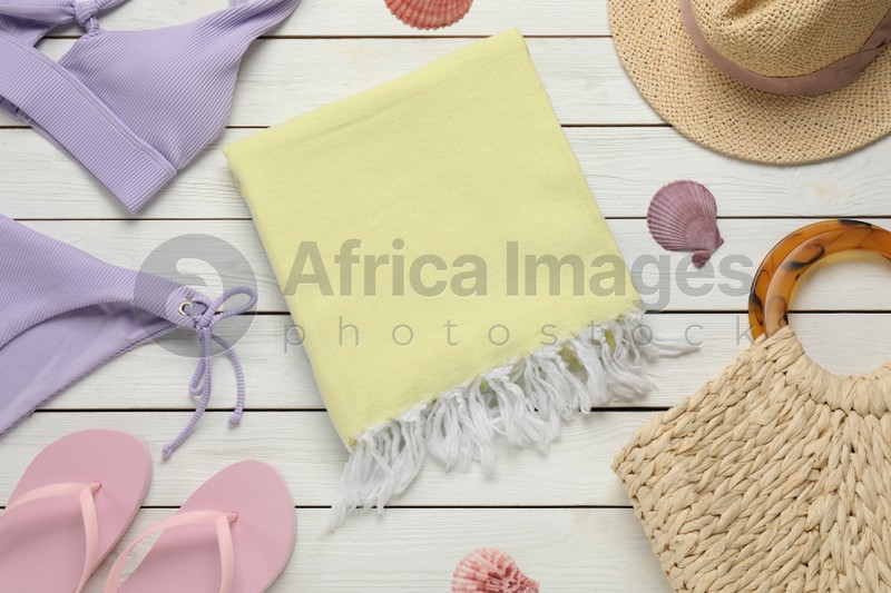 Towel and different beach items on white wooden background, flat lay