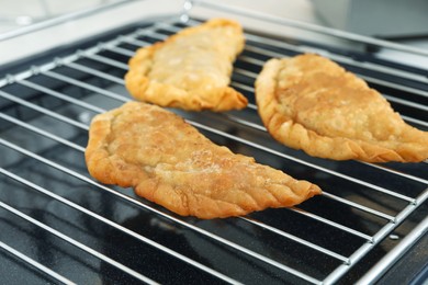 Photo of Delicious fried chebureki with tasty filling on metal grid