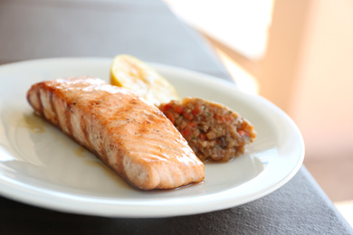 Delicious grilled salmon with garnish on plate, closeup