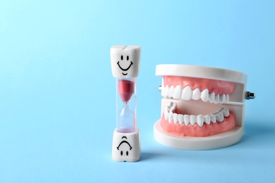 Dental hourglass and educational model of oral cavity with teeth on color background. Space for text
